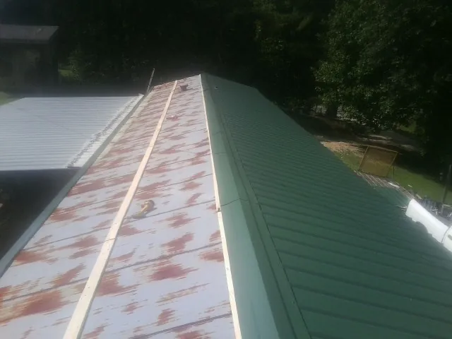 Old rusted panels beside newly installed green metal roofing — Wind Damage Roof Repair by Roofing Brothers in Bluffton