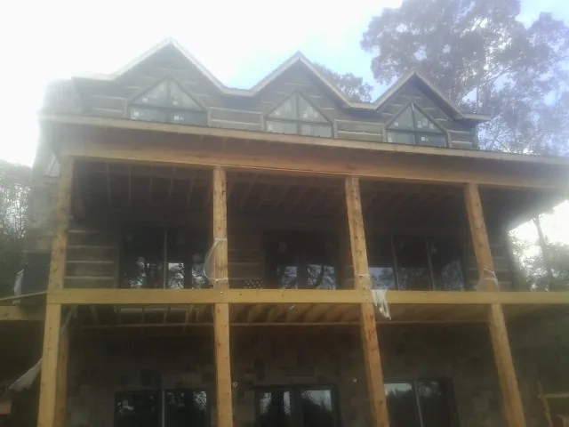 Dormers and porch framing on a large log home under construction — Roof Coating work by our crew in Bluffton